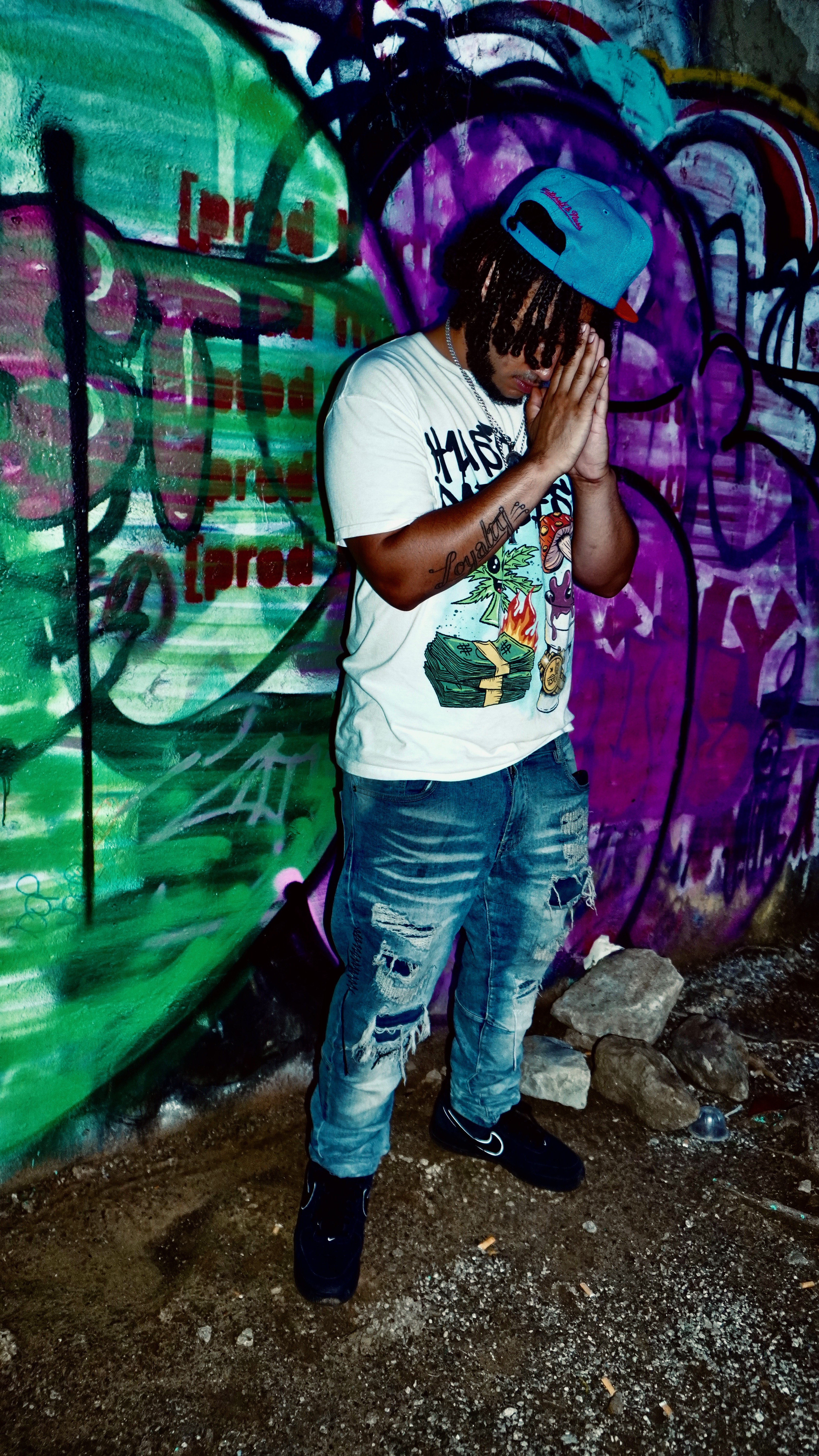 A3ThaGritKing standing in front of a colorful graffiti wall