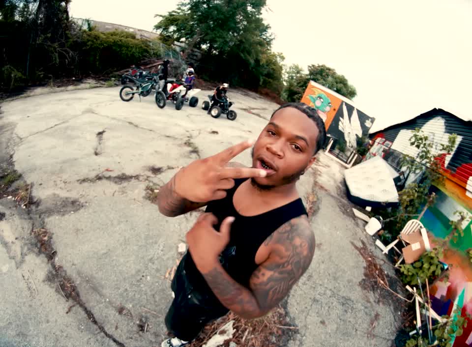 Fox BD rapping directly toward the camera with motorcycles and ATVs behind him.